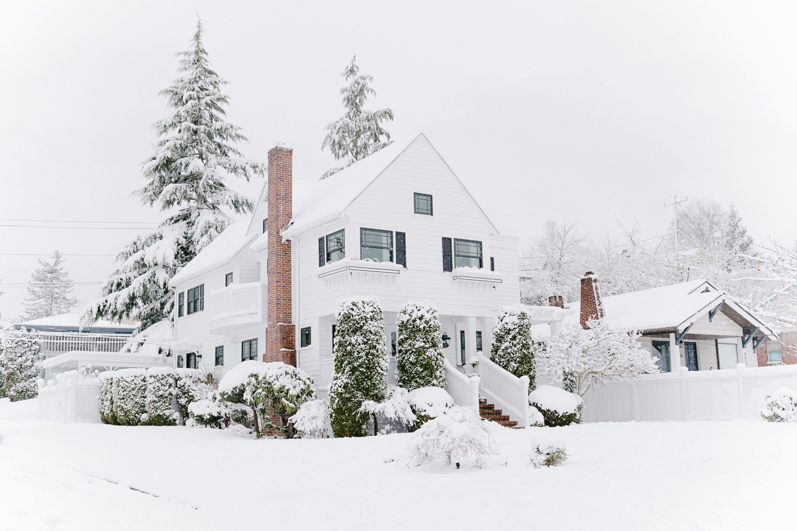 Home in the winter with snow on the roof and on the ground, schedule roof inspection before snowfall